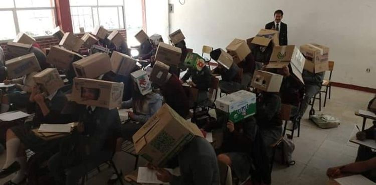 На фото мексиканский учитель вместе со студентами в картонных коробках на экзамене